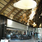 Palisade vertical rotating ceiling fan, antique brass, with natural palm leaf blades, in a hotel lobby
